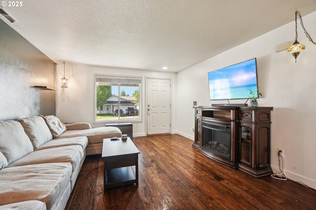 living room with a glass covered fireplace, baseboards, dark wood finished floors, and visible vents