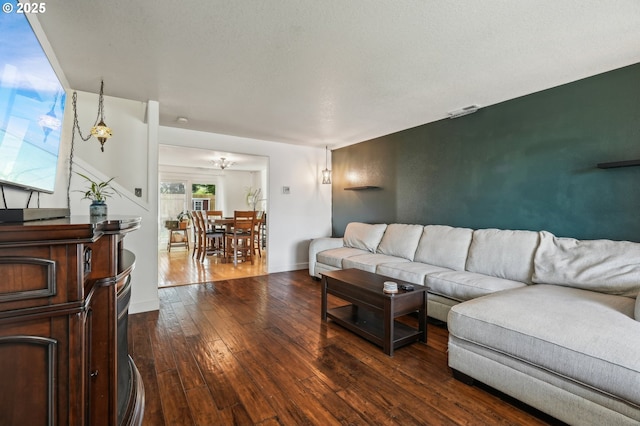 living room with baseboards, a notable chandelier, and dark wood-style floors
