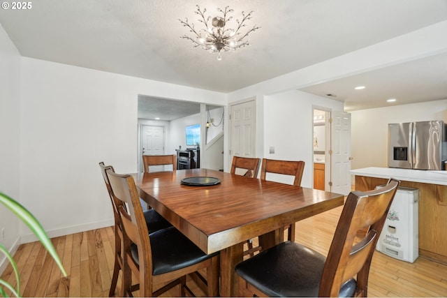 dining space with baseboards, recessed lighting, light wood-style flooring, and an inviting chandelier