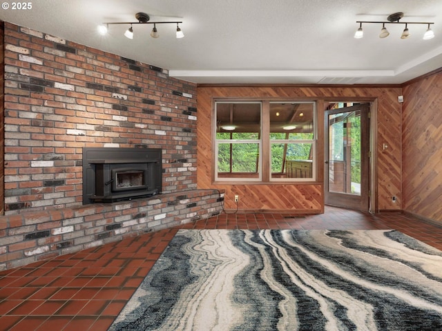 18036 NW Emmaus Ln, Portland, OR 97231 - unfurnished living room with track lighting, wooden walls, healthy amount of natural light, and a wood stove