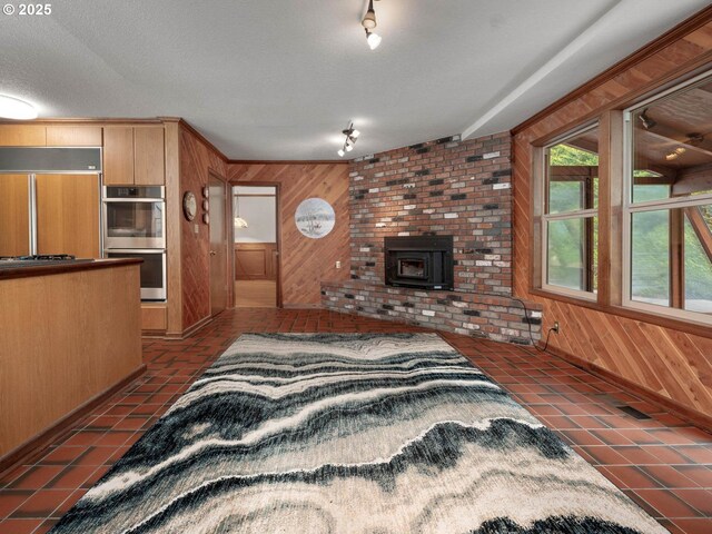 18036 NW Emmaus Ln, Portland, OR 97231 - living room featuring wood walls, a wood stove, dark tile patterned flooring, and track lighting