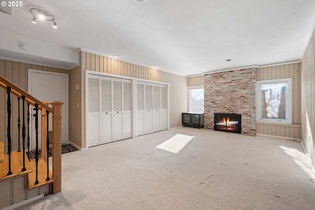 unfurnished living room with a brick fireplace, light carpet, and a textured ceiling