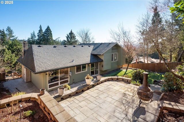 back of property with a fire pit and a patio area