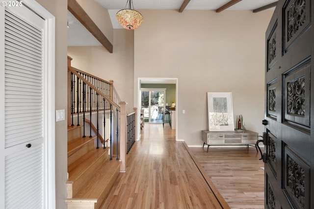 foyer entrance featuring a high ceiling, beamed ceiling, and light wood-type flooring