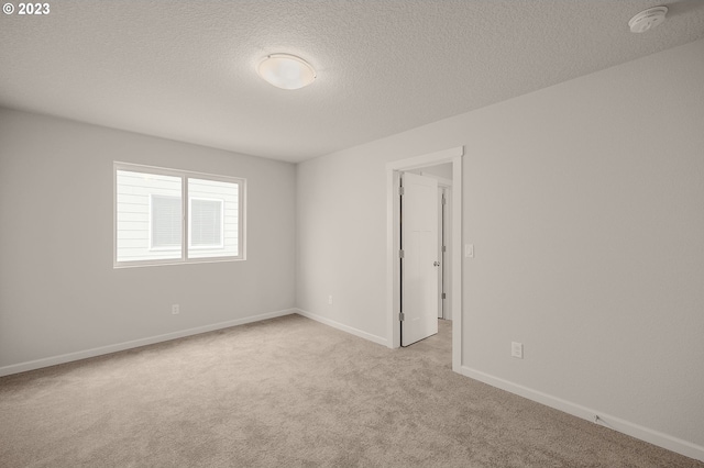 carpeted spare room with baseboards and a textured ceiling