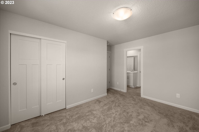 unfurnished bedroom featuring a sink, a closet, carpet floors, and baseboards