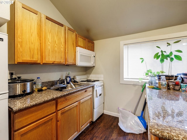 kitchen featuring dark wood-style floors, lofted ceiling, a sink, white appliances, and baseboards