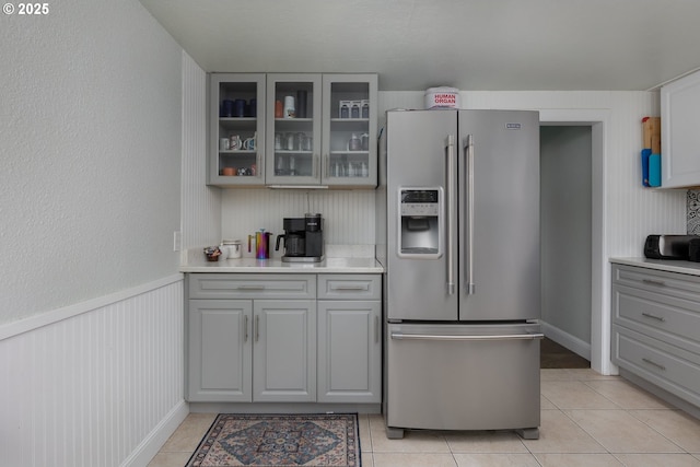 kitchen featuring gray cabinetry, glass insert cabinets, light tile patterned flooring, and high end refrigerator