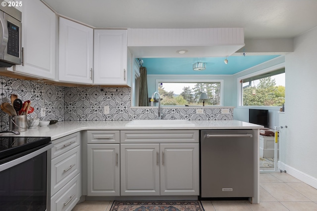 kitchen featuring light countertops, decorative backsplash, appliances with stainless steel finishes, white cabinetry, and a sink