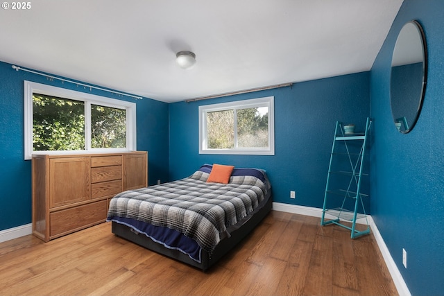 bedroom featuring wood finished floors, baseboards, and a textured wall