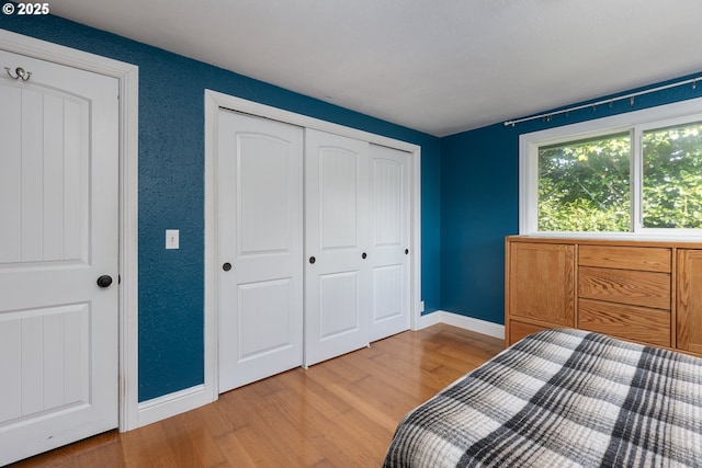 bedroom featuring a closet, light wood-style flooring, and baseboards