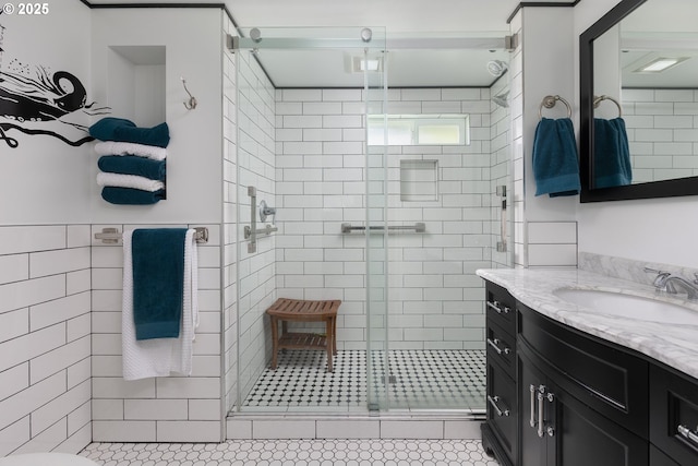 bathroom featuring a stall shower, vanity, and tile walls