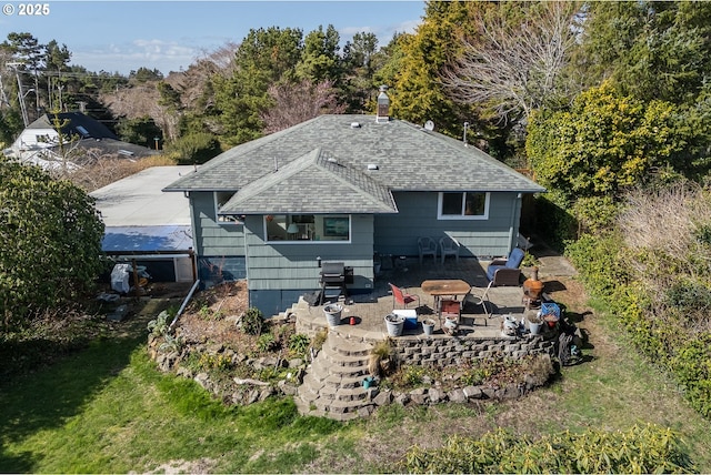 back of property with a patio, a yard, a chimney, and a shingled roof