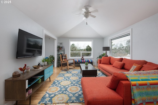 living room with light wood-style floors, ceiling fan, and vaulted ceiling