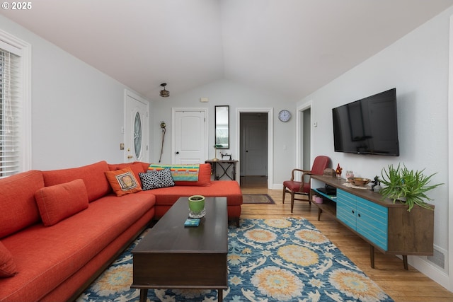 living room with vaulted ceiling, baseboards, and light wood finished floors