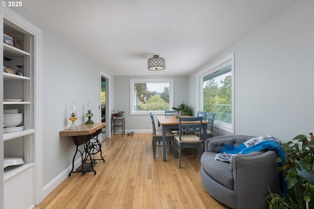 dining space featuring light wood-style flooring, built in features, and baseboards