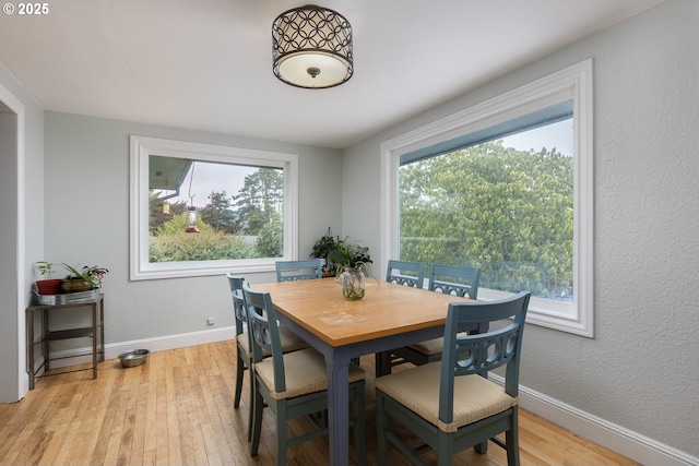 dining room with light wood finished floors, baseboards, and a textured wall