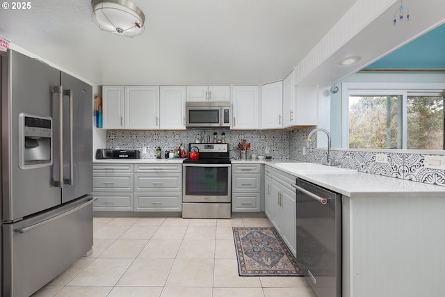 kitchen with light tile patterned floors, a sink, light countertops, appliances with stainless steel finishes, and tasteful backsplash