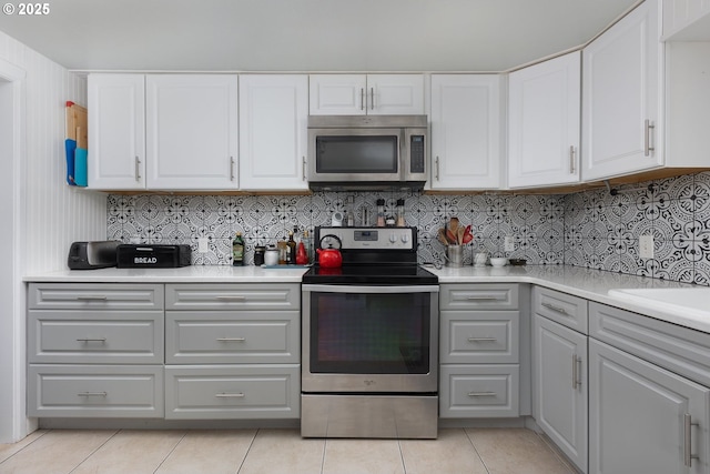 kitchen with light countertops, light tile patterned floors, gray cabinets, and appliances with stainless steel finishes