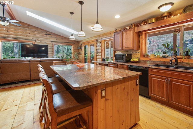 kitchen with black dishwasher, a center island, stainless steel microwave, vaulted ceiling with skylight, and a sink