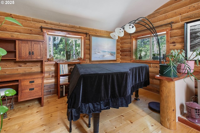 bedroom with light wood finished floors, rustic walls, and vaulted ceiling