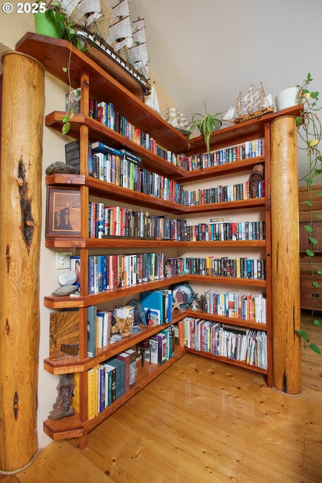 living area with wall of books and wood finished floors