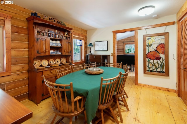 dining room with rustic walls, a healthy amount of sunlight, and light wood finished floors