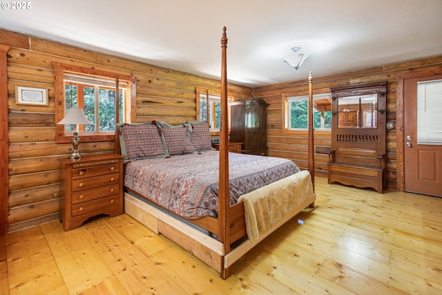 bedroom with log walls and wood-type flooring