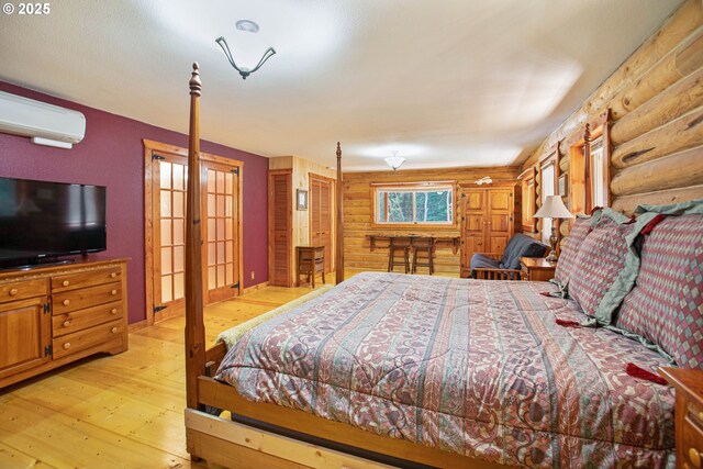bedroom featuring light wood-style floors, a wall mounted air conditioner, and rustic walls