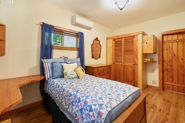 bedroom with baseboards, a wall unit AC, and wood finished floors