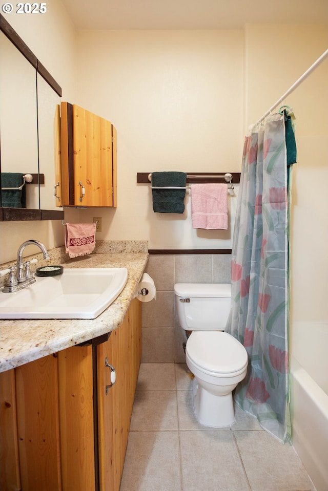 bathroom featuring tile patterned flooring, vanity, toilet, tile walls, and a wainscoted wall