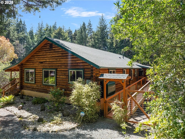 exterior space featuring log exterior, stairs, roof with shingles, and a wooden deck