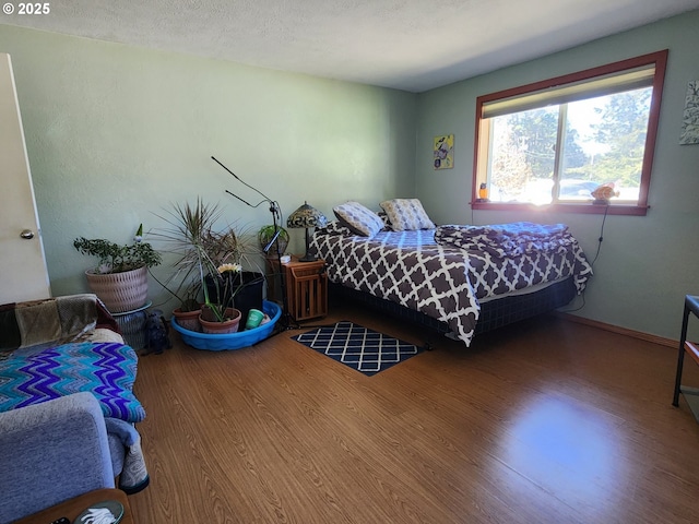 bedroom with a textured ceiling and wood finished floors