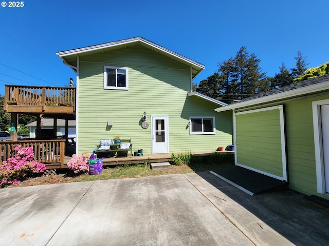 back of house with a deck and a patio