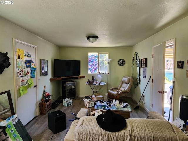 living area with a textured ceiling, baseboards, and wood finished floors