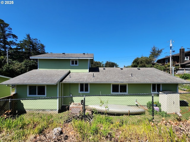 rear view of property featuring roof with shingles and fence