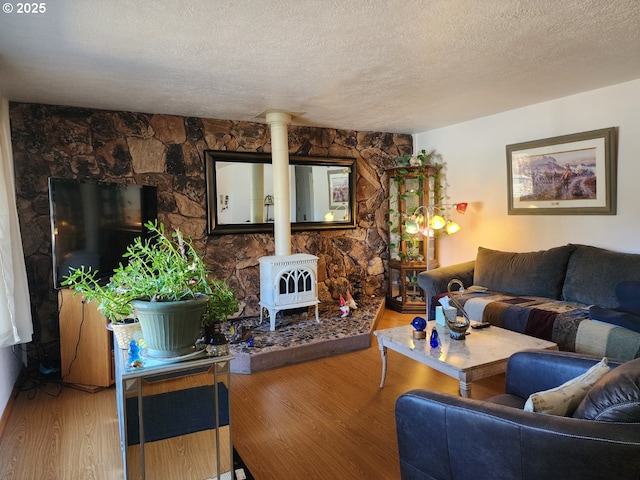 living room with a wood stove, a textured ceiling, and wood finished floors