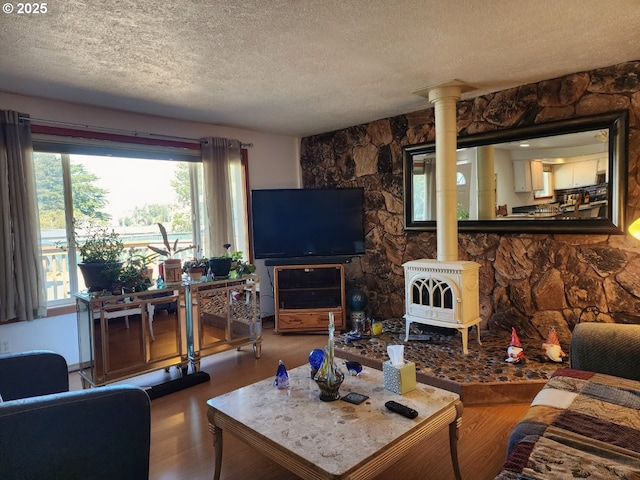 living area featuring a wood stove, a textured ceiling, and wood finished floors