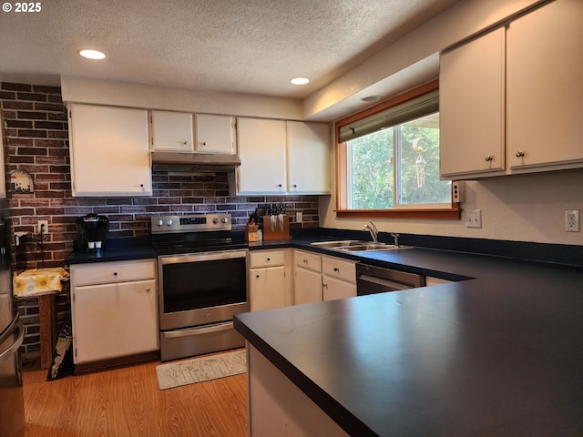 kitchen featuring a sink, dark countertops, light wood-type flooring, a textured ceiling, and electric stove