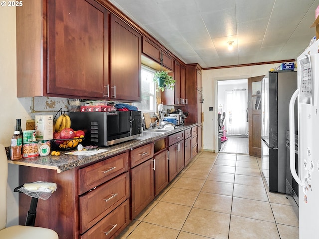 kitchen featuring light tile patterned flooring, dark stone counters, and appliances with stainless steel finishes