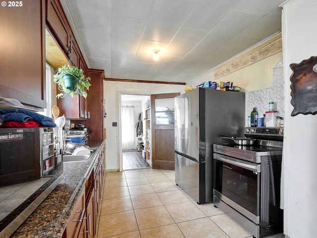 kitchen featuring stainless steel appliances, tasteful backsplash, dark stone countertops, crown molding, and light tile patterned floors