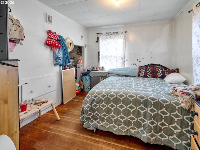 bedroom with ornamental molding and hardwood / wood-style flooring