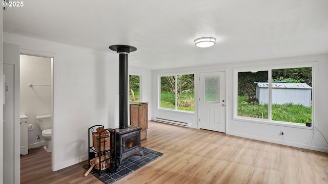 1298 N Tenmile, Lakeside, OR 97449 - living area with a wood stove, a baseboard radiator, baseboards, and wood finished floors