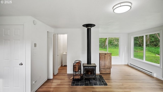 1298 N Tenmile, Lakeside, OR 97449 - living area with a wood stove, baseboard heating, baseboards, and wood finished floors