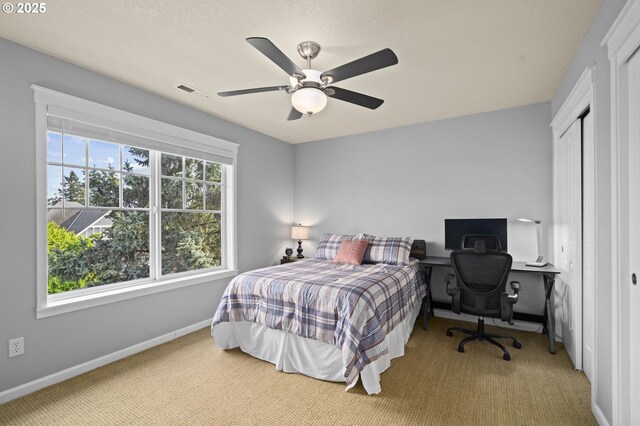 carpeted bedroom featuring baseboards, a ceiling fan, and visible vents