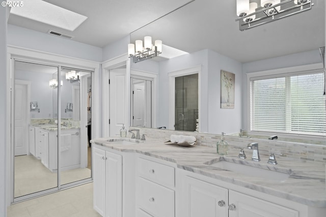 bathroom with visible vents, a sink, a chandelier, and double vanity