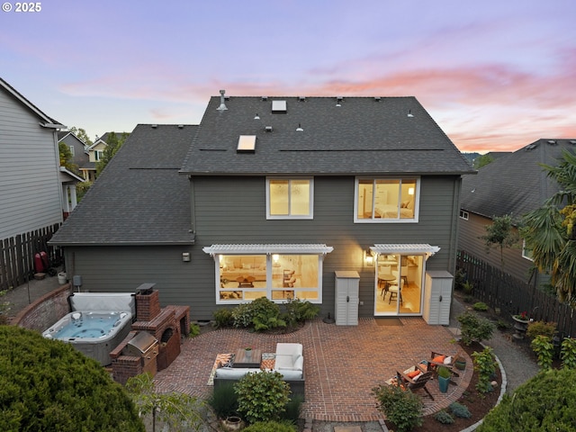 back of property with a patio area, fence, an outdoor hangout area, a covered hot tub, and a shingled roof