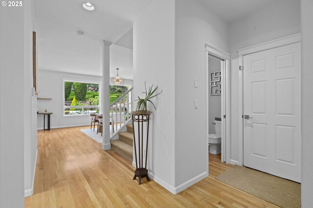 hallway featuring baseboards, light wood-style flooring, and stairway