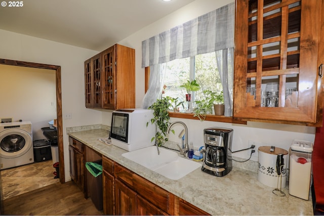 kitchen with light stone counters, washer / clothes dryer, white microwave, and a sink