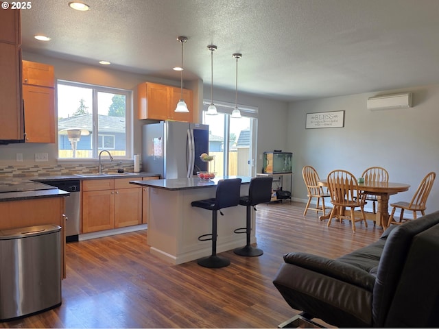 755 Nebraska St, Eugene, OR 97402 - kitchen with stainless steel appliances, a sink, an AC wall unit, a breakfast bar, and dark wood-style floors